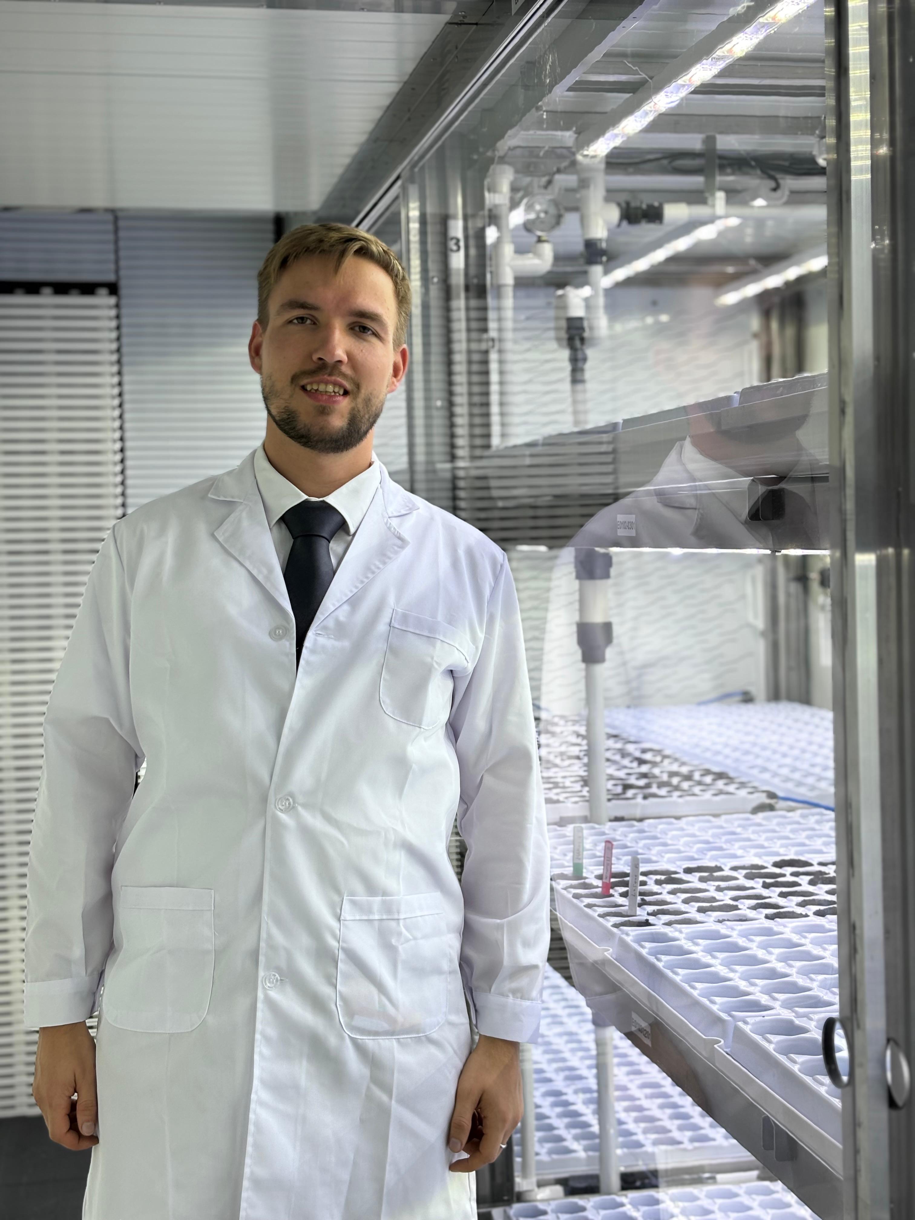 Portrait of Ilia Sukhodolov inside a greenhouse corridor